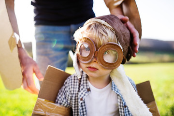 Happy toddler boy playing outside with father in spring nature.