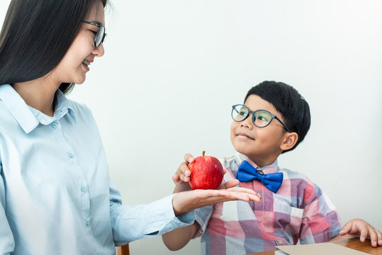 Schoolboy Smiling And Giving Red Apple To His Teacher