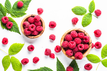 Fresh raspberries in wooden bowl on white table. 