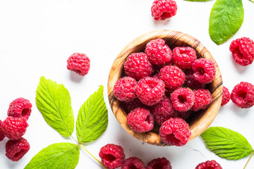 Fresh raspberries in wooden bowl on white table. 