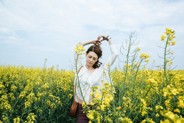 Portrait of fashionable young woman in the yellow flowers field
