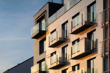 Golden facade of a multistorey building with balconies, background at the sunset