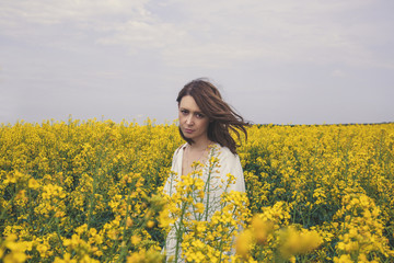 Portrait of fashionable young woman in the yellow flowers field
