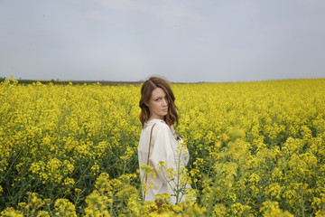 Fototapeta premium Portrait of fashionable young woman in the yellow flowers field 