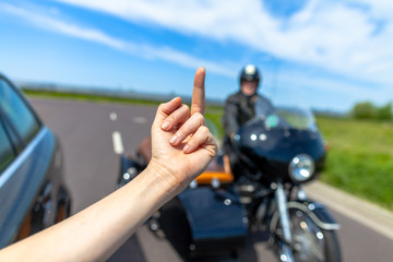 a car driver shows his middle finger to a  biker