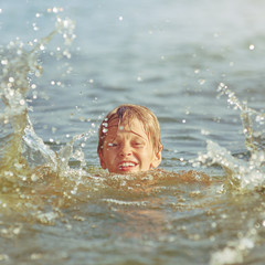 Portrait of young serious boy swimming in the lake at summer, image with square aspect ratio and...