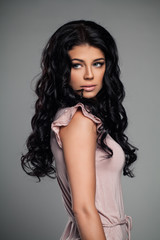 Naklejka premium Fashion Portrait of Stylish Brunette Woman in Pink Dress. Elegant Female Model with Curly Hairstyle