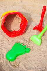 Fototapeta na wymiar children's sandbox and colorful plastic toys pail bucket and rake for playing outdoors in the summer day concept of development and recreation of children with copy space