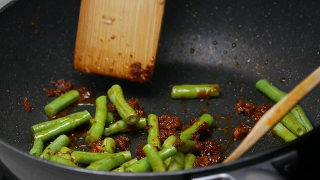 stir fried yard long beans , the spices , curry paste  , food palm oil  together in the black teflon pan and with wooden turner.