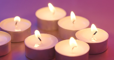 Fototapeta na wymiar Burning candle under purple and blue light