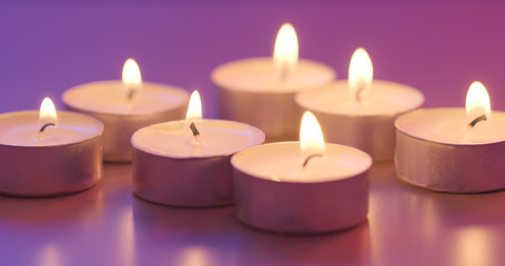 Fototapeta na wymiar Burning candle under purple and blue light