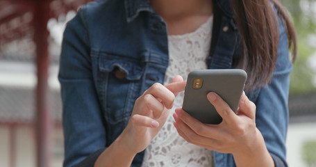 Woman work on smart phone in Chinese garden