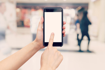 Hand woman holding and using phone with blurred background in shopping mall.