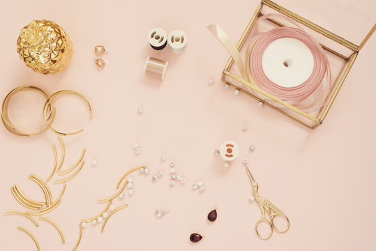 Jewelry designer workplace. Handmade, craft concept. Materials for making jewelry ? golden scissors, ribbons, gold tubes, bracelet settings. Freelance workspace in flat lay style