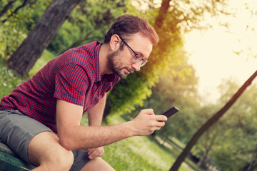 Modern guy texting on his cellphone in nature.