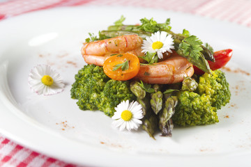 Prawns, asparagus and broccoli with edible daisy flowers. Selective focus.