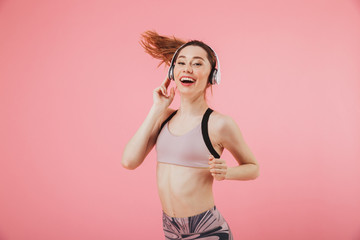 Happy sportswoman in headphones running and listening music