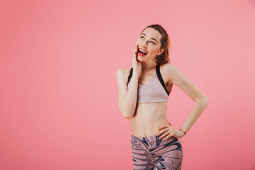 Obraz premium Pensive sportswoman posing with arm on hip while looking up