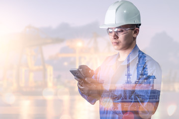 the double exposure image of the engineer using a smartphone overlay with oil refinery image.The concept of modern life, engineering, construction and internet of things.