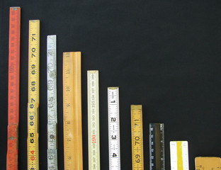Rulers and scales in metric and inches descend along a chart or graph representing measurement,...