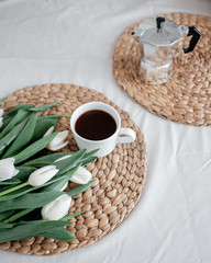 A bouquet of white tulips and a cup of coffee on a table