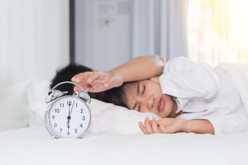 Sleepy man trying turn off alarm clock beside a woman annoyed by noisy alarm clock in the morning