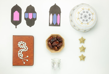 Table top view aerial image of decoration Ramadan Kareem holiday background.Flat lay date in wood basket with white rosary & lighting.The holy book of Koran on modern rustic white wood at office desk.