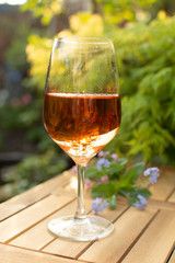 Trendy orange wine served on outdoor terrace in garden with flowers