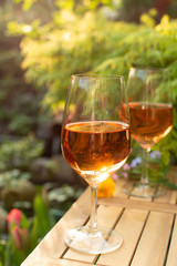 Trendy orange wine served on outdoor terrace in garden with flowers