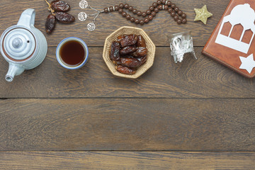 Table top view aerial image of decoration Ramadan Kareem holiday background.Flat lay date in wood basket with  rosary & green tea.Halal meal set for fasting is obligatory for Muslim on brown wooden.