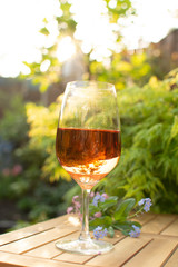 Trendy orange wine served on outdoor terrace in garden with flowers