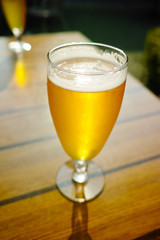 One cold light unfiltered beer in glass served on sunny outdoor terrace in garden