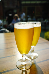 Two cold light unfiltered beer in glasses served on sunny outdoor terrace in garden