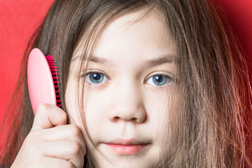 Sweet girl is combed on a red background