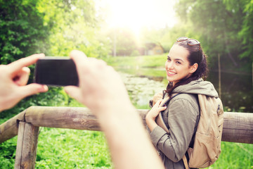 travel, hiking, backpacking, tourism and people concept - smiling couple with backpacks taking picture by smartphone in nature