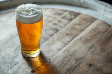 Glass of light beer on a wooden barrel