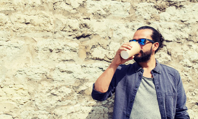 people, drinks, leisure and lifestyle - man drinking coffee from disposable paper cup on city street