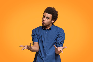 Beautiful male half-length portrait isolated on orange studio backgroud. The young emotional afro man