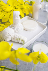 Bright spa background: candles and thai massage herbal bags with bottles and yellow flowers on пкун. Health, skin treatment conceptю Еуче ызфсу