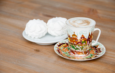 bright cup of cappuccino coffee with marshmallow close-up