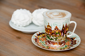 bright cup of cappuccino coffee with marshmallow close-up
