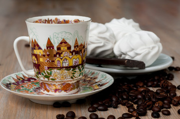 bright cup with coffee beans and sweets on a wooden table