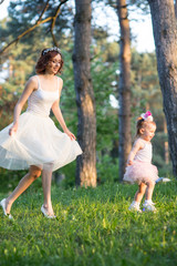 Mom and daughter are two years old sitting on the grass in the park