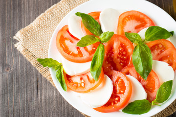 Close-up photo of caprese salad with ripe tomatoes, basil, buffalo mozzarella cheese. Italian and Mediterranean food concept. Fresh and healthy organic meal. Starter and antipasti. 