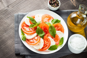 Close-up photo of caprese salad with ripe tomatoes, basil, buffalo mozzarella cheese. Italian and Mediterranean food concept. Fresh and healthy organic meal. Starter and antipasti. 