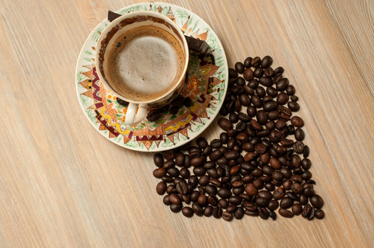 bright cup with coffee beans and sweets on a wooden table © Oksy001