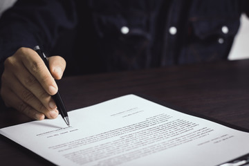 businessmna writing and sign on business contract on working table