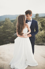 Beautiful happy young wedding couple posing on a background of rock cliff
