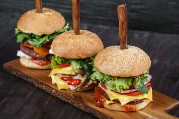 Delicious fresh hamburgers served on wooden plank with knife