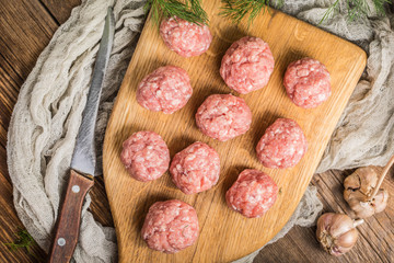 Raw meatballs on the wooden cutting board.